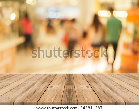 Wooden board empty table in front of people shopping at market fair background. Perspective wood and blur market - can be used for display or montage your products - vintage effect style pictures.