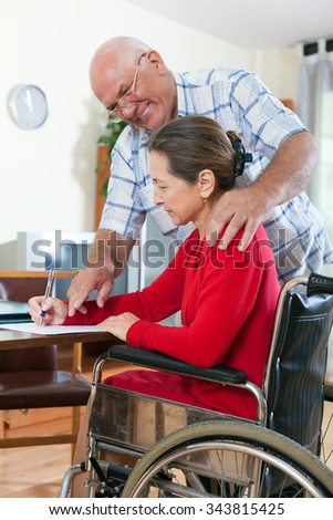 Mature woman in   wheelchair and   elderly man near . 