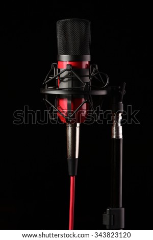 Professional recording studio condenser microphone attached to shock mount, isolated on black background