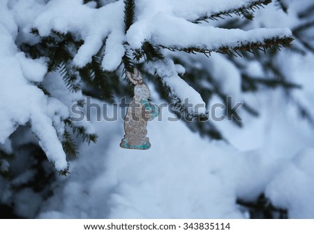 New Year toy. Paper rabbit on snow covered fir tree branch. New Year handmade decor.