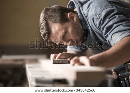 Portrait of handsome precise cabinetmaker during work in workshop Royalty-Free Stock Photo #343842560