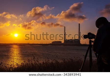 photographer at sunrise on the coast, on a background of giant pipes 