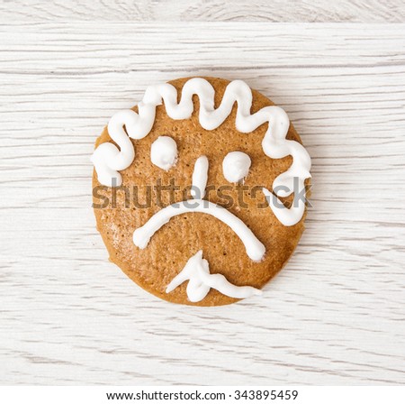 Gingerbread unhappy face on the wooden background. Christmas symbol.