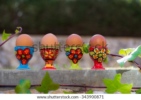 Row of four boiled eggs in colorful egg cups natural background. Easter egss in beautiful ceramic tableware, perfect for food, health, diet blogs and magazines