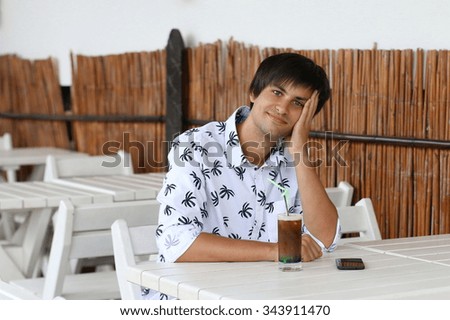 Young handsome man in a cafe with a cocktail