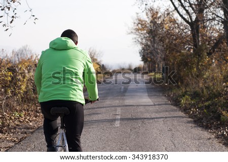 Rear View Of Young Man Enjoying Cycle Ride In Countryside