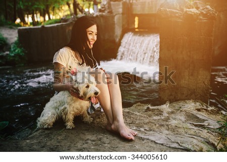 girl playing with a dog on the bank of the river near the bridge