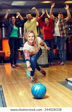 people, leisure, sport and entertainment concept - happy young woman throwing ball in bowling club