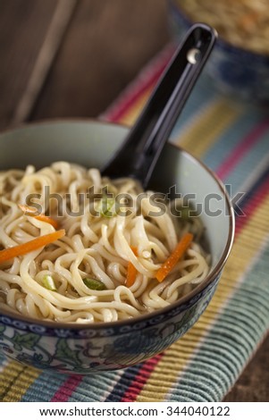 Asian soup with noodles in a decorated bowl on a wooden table