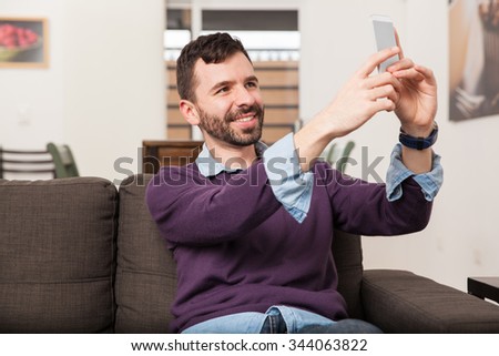 Happy young man with a beard taking a selfie for his social media profile picture with his smartphone
