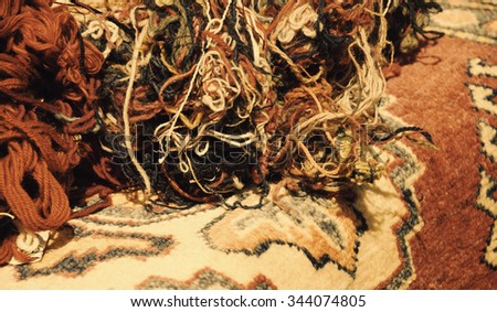 Oriental carpets and tangled wool threads in the market. "From material to product" concept. Selective focus on the threads. Aged photo. Sepia.