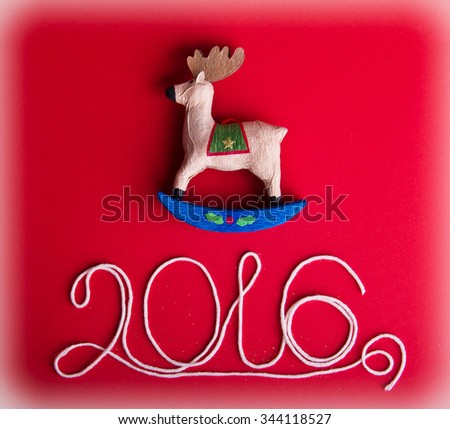 Decorative toy moose or deer on hot red background. Christmas and 2016 New Year theme. Place for your text, wishes, logo. Vignetted.