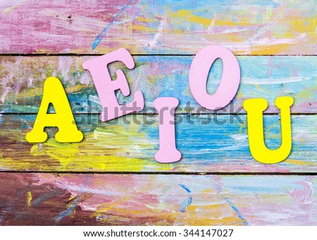 Word design " A E I O U " show English Vowel by letterpress on painted wooden background