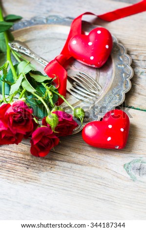 Table setting for St. Valentines day with glasses of red wine, present box and red roses  in rustic style