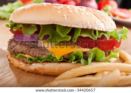 cheeseburger and french fries on a wooden table with ingredients