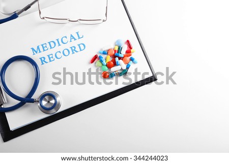 Stethoscope with medical record and pills isolated on white