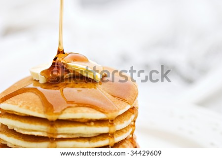 Thick maple syrup pouring onto a stack of fresh pancakes. Selective focus on butter with blurred background. Royalty-Free Stock Photo #34429609