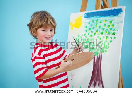 Happy boy painting his picture on an easel