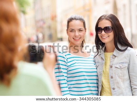 tourism, travel, leisure, holidays and friendship concept - smiling teenage girls with camera outdoors