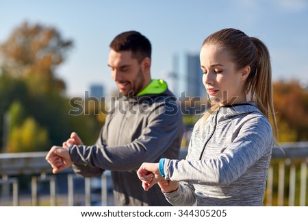 fitness, sport, people, technology and healthy lifestyle concept - smiling couple with heart-rate watch running over city highway bridge Royalty-Free Stock Photo #344305205