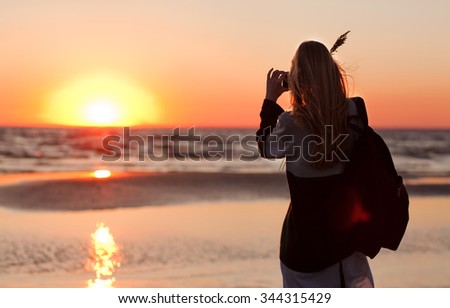 Young blond woman taking picture of a beautiful sunset