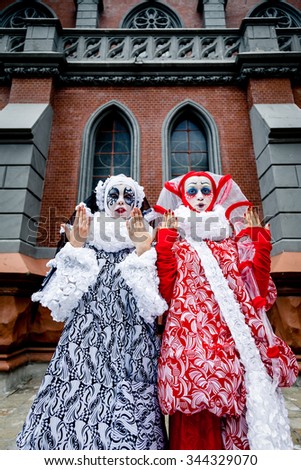 Two cheerful female clowns dressed in black and white cloth outdoors