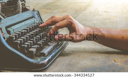 Vintage typewriter and human hand on a wood table , process in vintage style