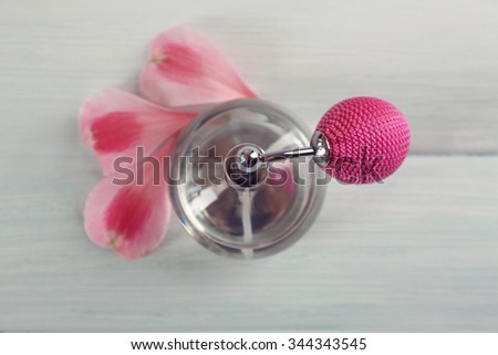 Bottle of perfume and flowers petals on wooden background