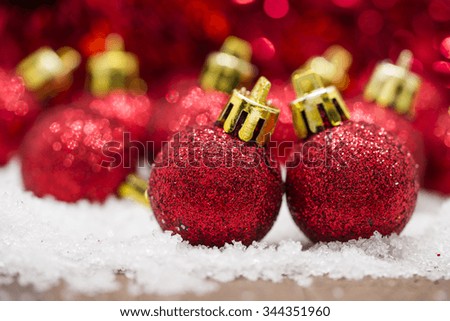 Red Christmas balls on snow against red bokeh background.