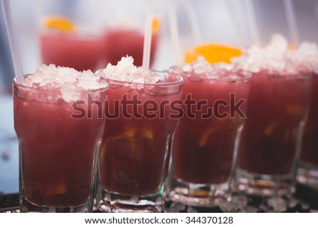 Beautiful row line of different colored alcohol cocktails with mint on a party, martini, vodka with bubbles,and others on decorated catering bouquet table on open air event, picture with bartender