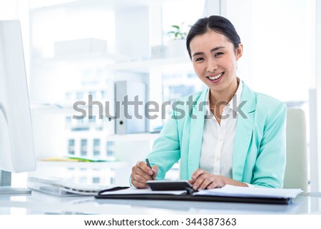 Smiling businesswoman with notes at desk in work