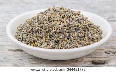 Dried lavender herbal tea in white bowl over wooden background