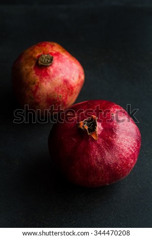 Whole pomegranate on a wooden table. Background fades from brown to black with copy space