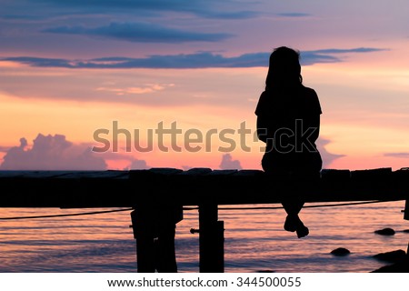 Lonely woman sitting on a wooden bridge sunset.are Lonely. style abstract shadows.silhouette Royalty-Free Stock Photo #344500055