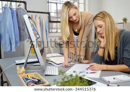Two Fashion Stylist Women Sketching a New Design on a White Paper at the Table Inside the Office.