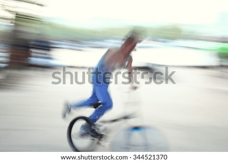 The blurry photo of street entertainer ride on the bicycle represent the outdoor activity and entertain concept related idea.