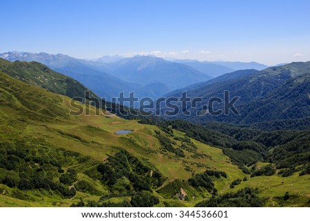 small mountain lake on the green alpine meadows and valley covered with forest in caucasus mountains in Auadhare Abkhazia Georgia 