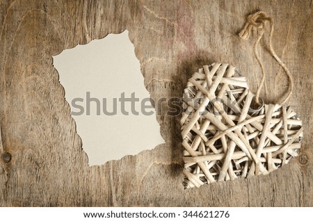wicker heart handmade lying on a wooden base with a sheet of paper