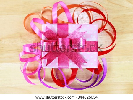 Gift box and colorful of ribbon on wood background.