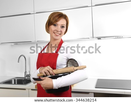 sweet cook woman wearing red apron holding cooking pot and rolling pin at home kitchen smiling happy in domestic cooking and lifestyle concept 