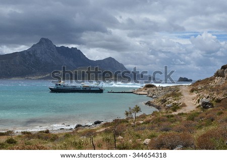 Touristic cruise ship at a small harbour ( with turquoise water ) of the pirate island Gramvousa.Tourists go on land and explore surrounding area.Balos bay on backdrop.Near with Crete.Greece.Europe.
