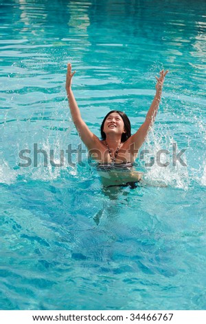 Pretty asian girl splashes in a pool