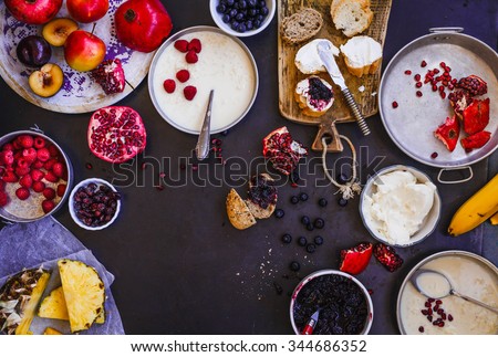 Family morning breakfast tabletop with rice milk plate, sliced tropical fruits, berry, spread cream cheese bread in various plate. Rustic dark style. Royalty-Free Stock Photo #344686352