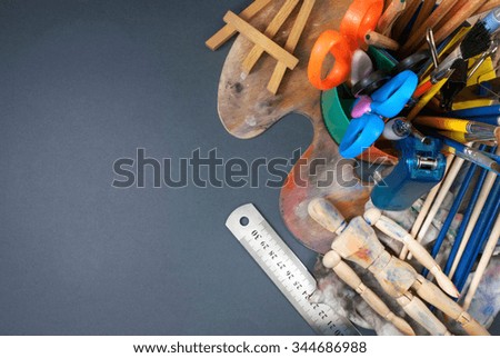 Multiple art tools and classic wooden dummy on a gray background.