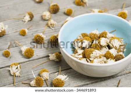 dried chamomile flower heads on old wood table 