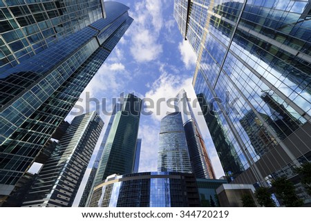 Business office skyscrapers, looking up at high-rise buildings in commercial district, architecture raising to the blue sky with white clouds, bottom view  Royalty-Free Stock Photo #344720219