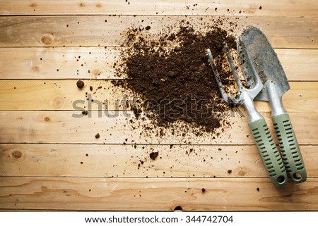 Small gardening shovel and fork on wooden background.
