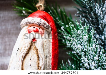 Cute wooden Santa Clays Christmas tree toy with pine snowy twig on a shabby wooden table