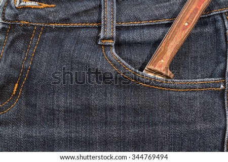 Old knife with a wooden handle in your pocket jeans. Texture.