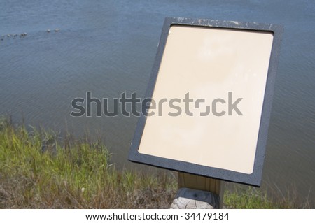 An educational display in a natural setting with grass, and ocean.  Depth of field shot with focus on the empty sign.  Photograph was taken in North Carolina.